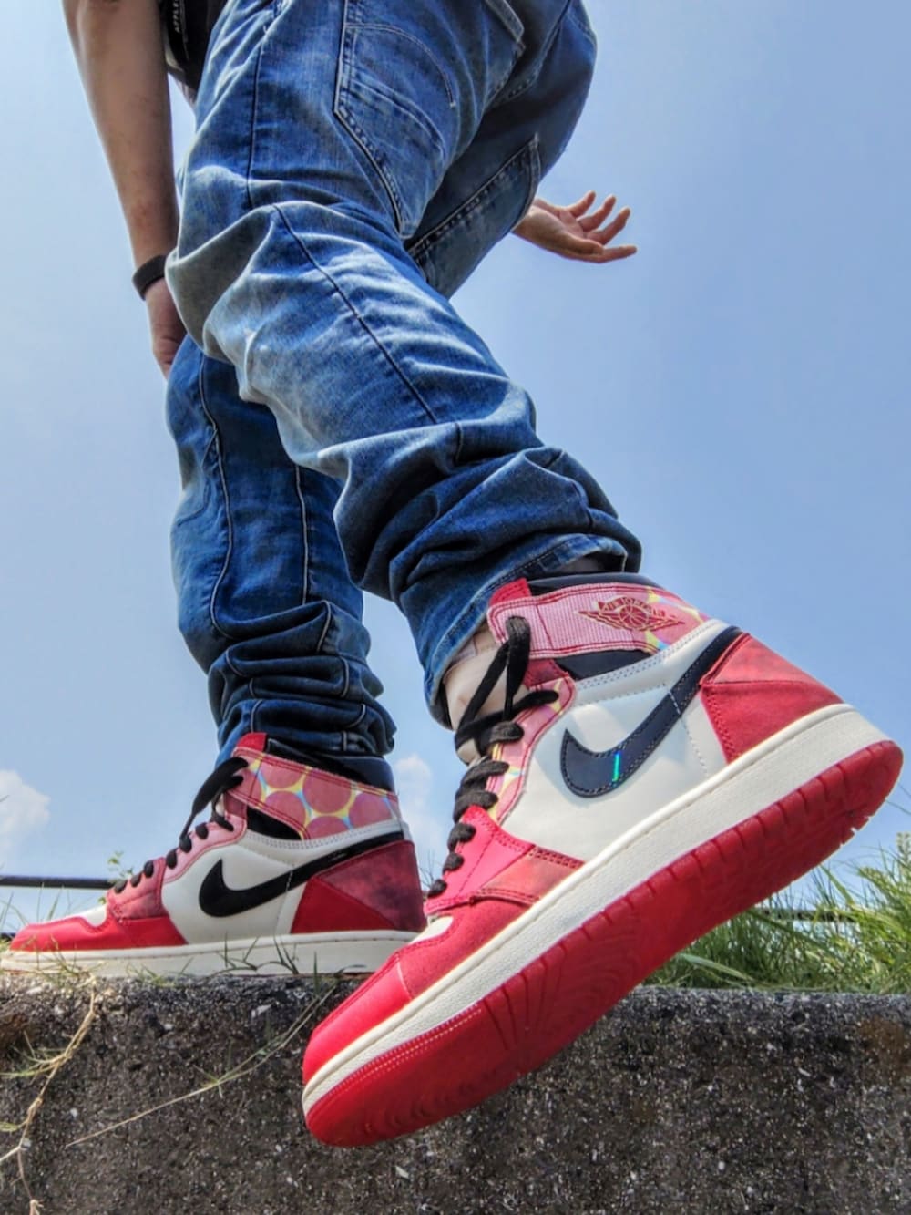 ブラック系のTシャツ/カットソー、ブルー系のデニムパンツ、レッド系のスニーカーを着用したメンズの夏コーディネートの2枚目の写真