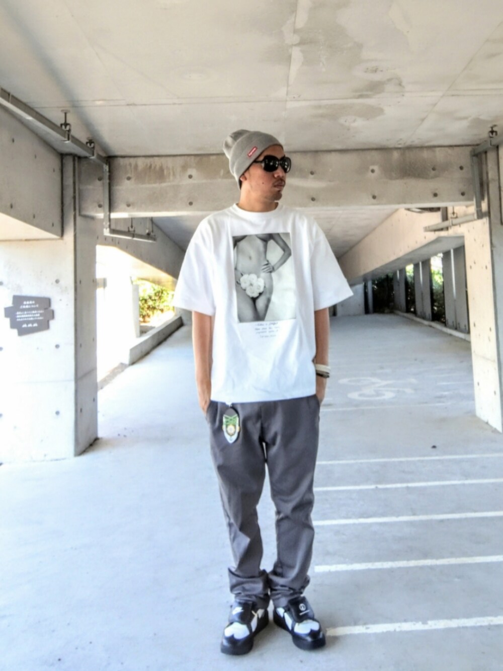 ホワイト系のTシャツ/カットソー、グレー系のチノパンツ、ブラック系のスニーカーを着用したメンズの夏コーディネートの3枚目の写真