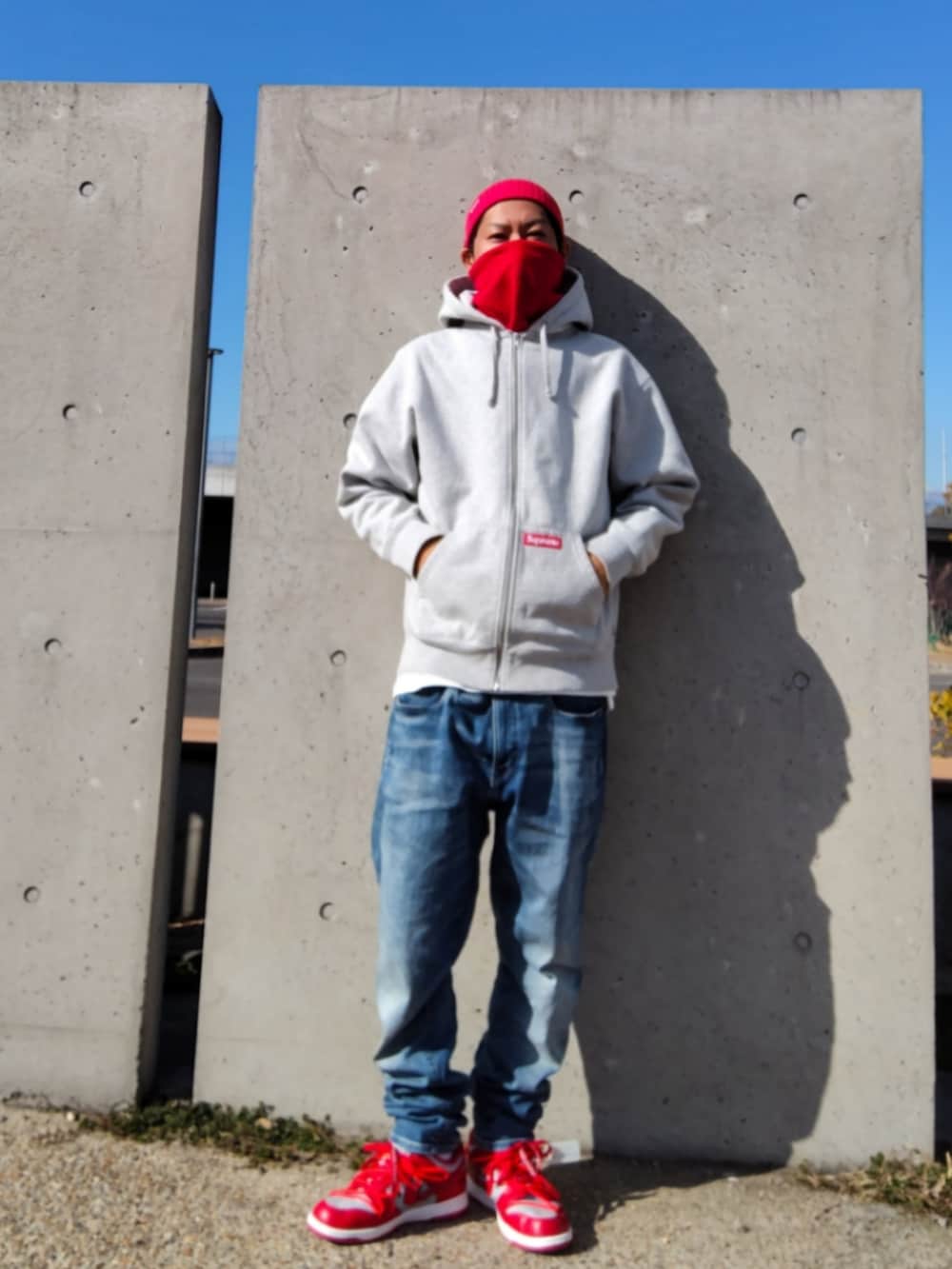 グレー系のパーカー、ブルー系のデニムパンツ、レッド系のスニーカーを着用したメンズの冬コーディネートの3枚目の写真