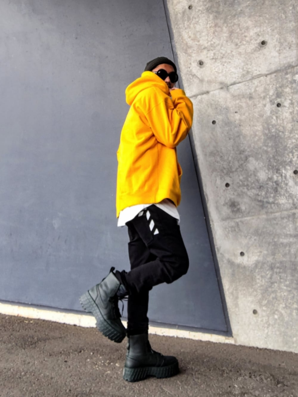 イエロー系のパーカー、ホワイト系のタンクトップ、ブラック系のデニムパンツを着用したメンズの冬コーディネートの3枚目の写真