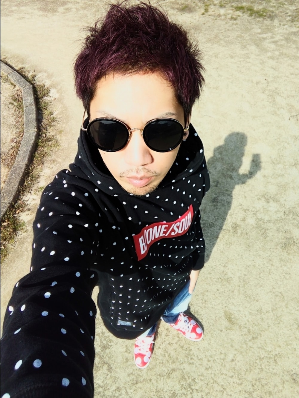 ブルー系のデニムパンツ、レッド系のスニーカー、ブラック系のパーカーを着用したメンズの春コーディネートの3枚目の写真