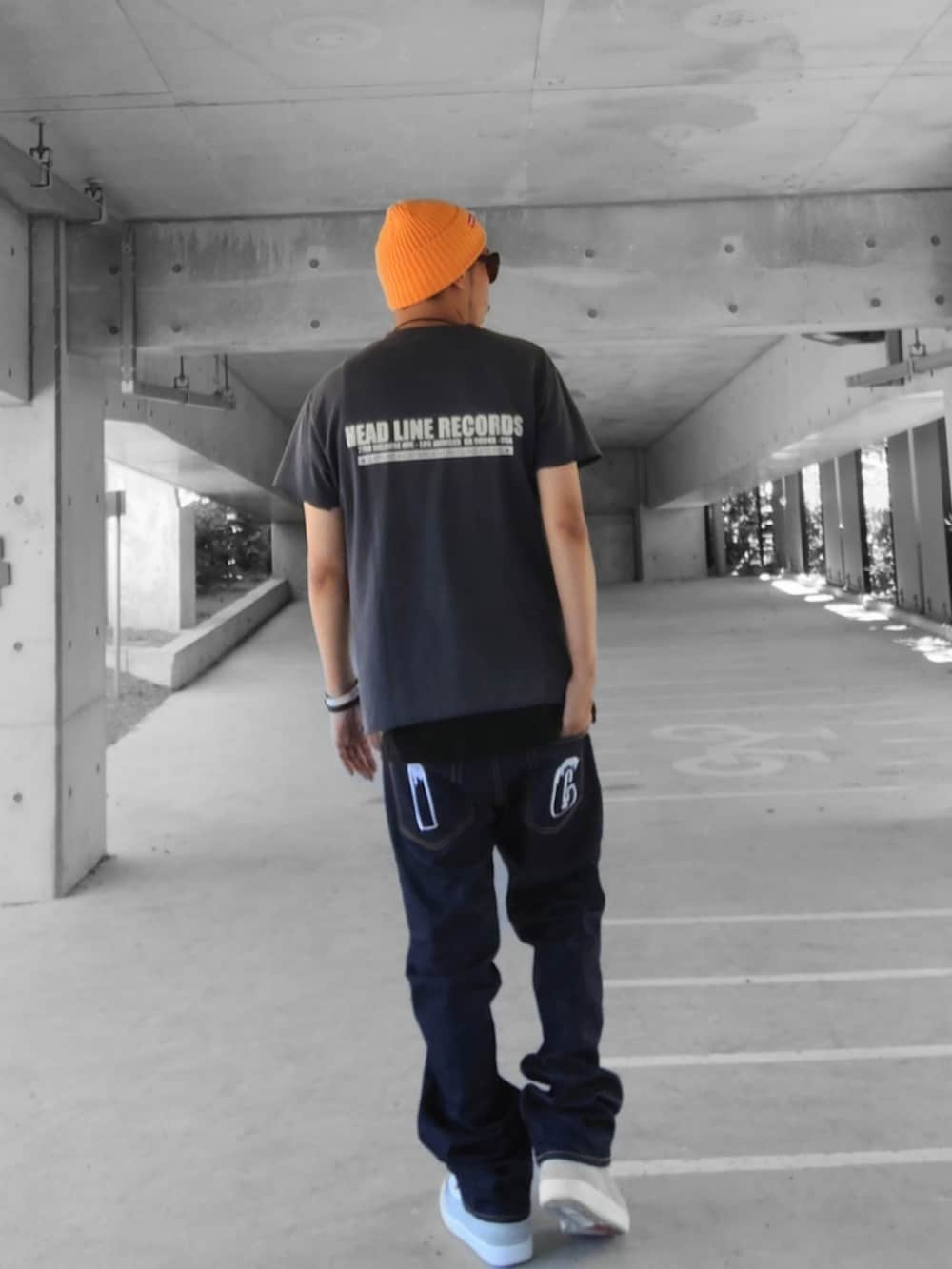 ブラック系のタンクトップ、ブルー系のデニムパンツ、グレー系のスニーカーを着用したメンズの夏コーディネートの3枚目の写真