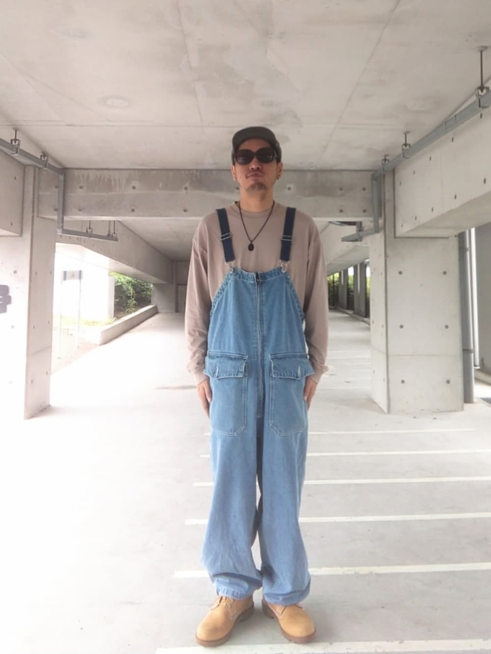 イエロー系のブーツ、ブルー系のサロペット/オーバーオール、ベージュ系のTシャツ/カットソーを着用したメンズの夏コーディネートの2枚目の写真