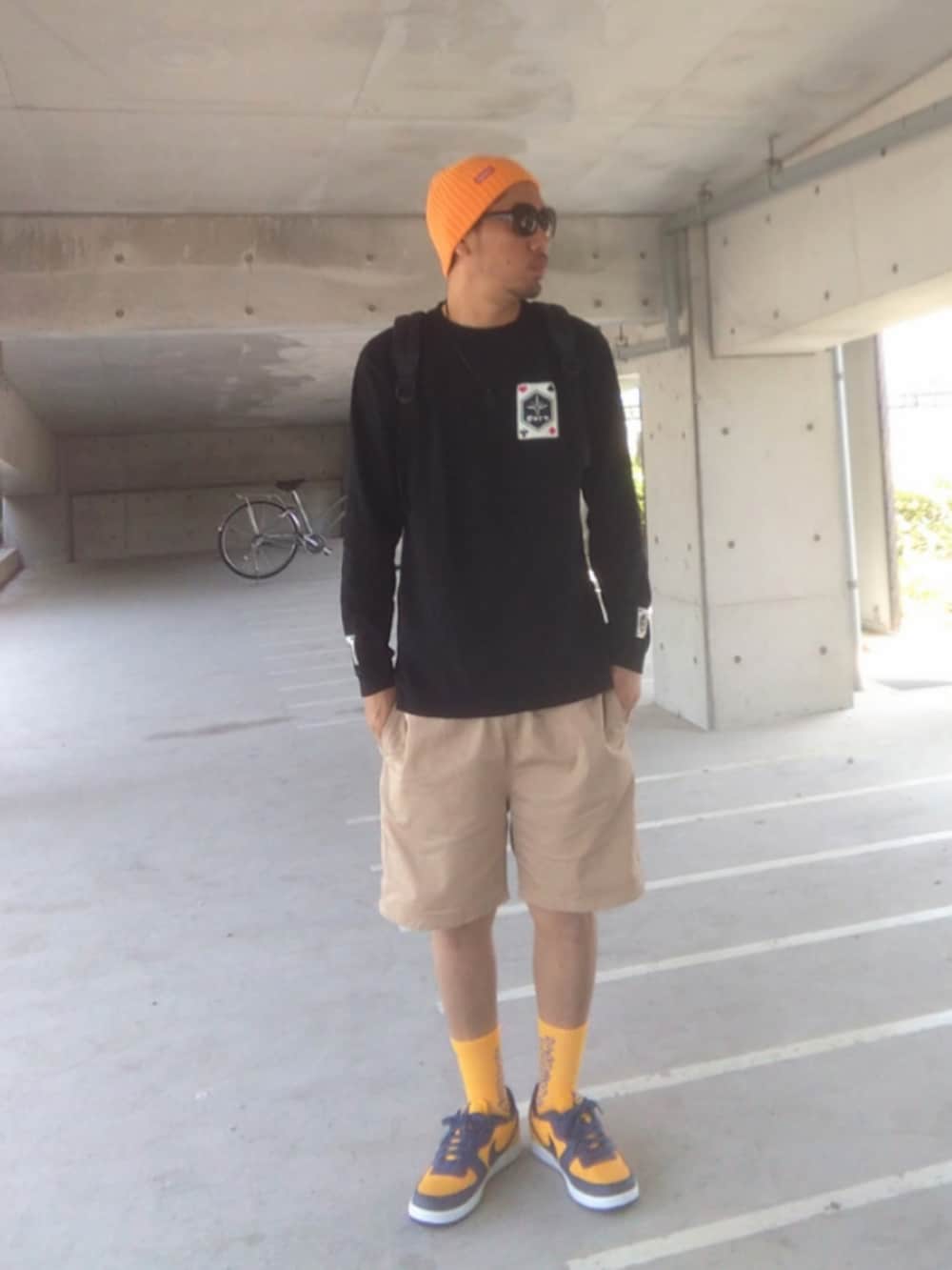 ブラック系のTシャツ/カットソー、ベージュ系のチノパンツ、ブラック系のバックパック/リュックを着用したメンズの春コーディネートの2枚目の写真