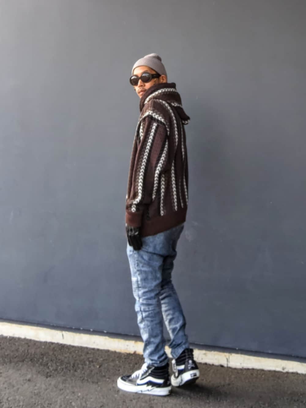 ブラウン系のパーカー、ブルー系のデニムパンツ、ブラック系のスニーカーを着用したメンズの冬コーディネートの3枚目の写真