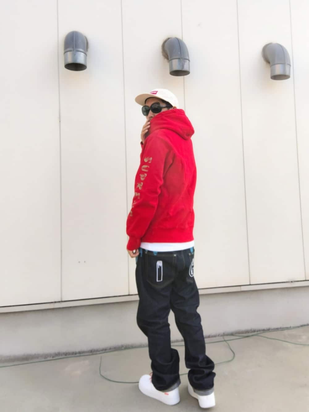 レッド系のパーカー、ホワイト系のタンクトップ、ブルー系のデニムパンツを着用したメンズの秋コーディネートの3枚目の写真