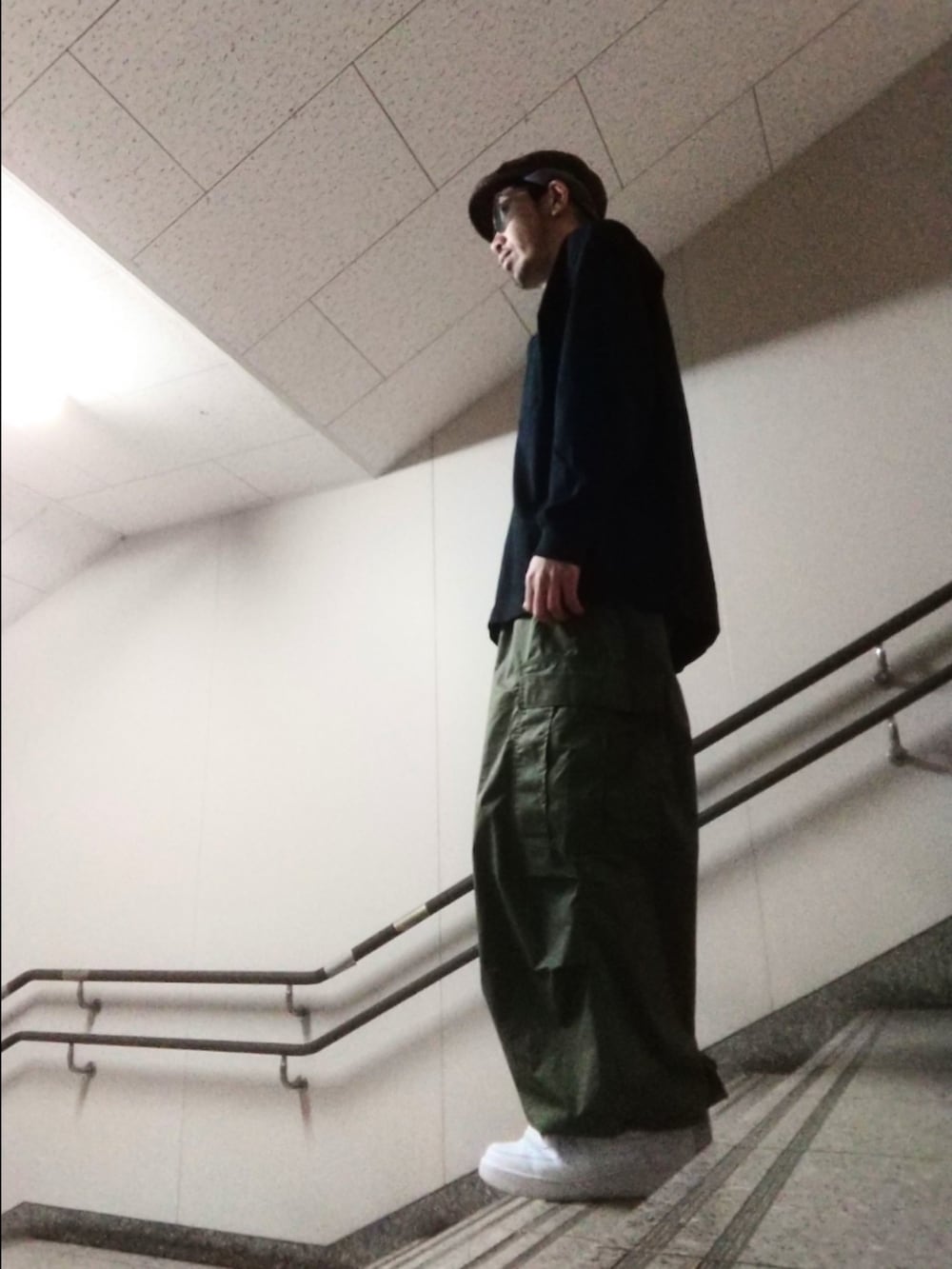 ブラック系のTシャツ/カットソー、グリーン系のその他パンツ、ホワイト系のスニーカーを着用したメンズの春コーディネートの2枚目の写真