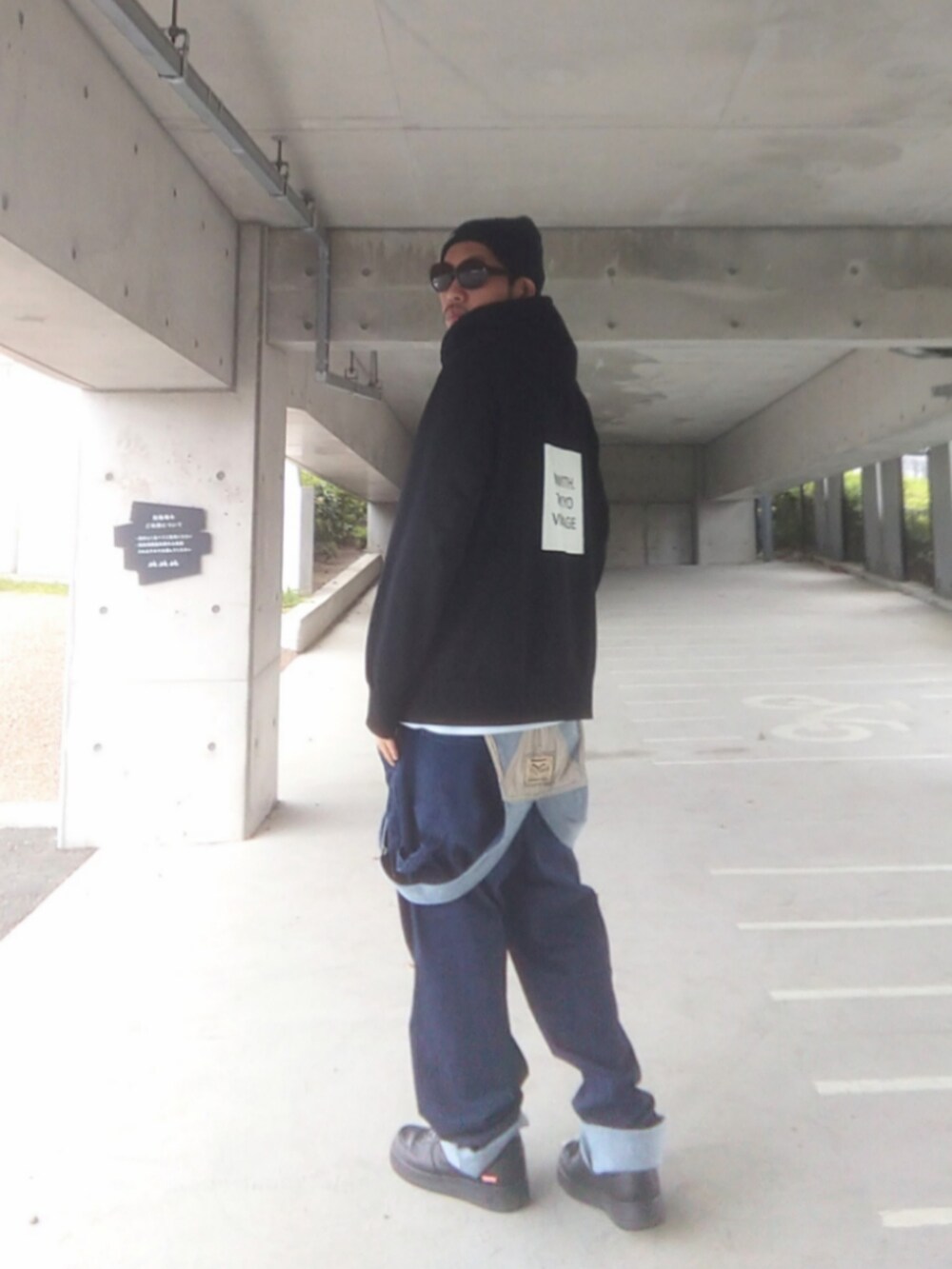 ブラック系のパーカー、ブルー系のサロペット/オーバーオール、ブラック系のスニーカーを着用したメンズの春コーディネートの3枚目の写真