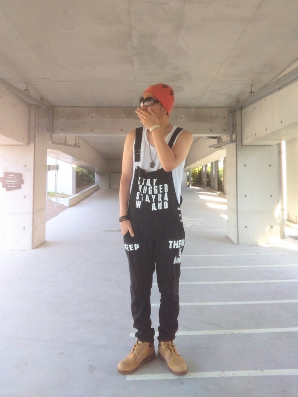 ブラック系のサロペット/オーバーオール、イエロー系のブーツ、オレンジ系のニットキャップ/ビーニーを着用したメンズの秋コーディネートの3枚目の写真