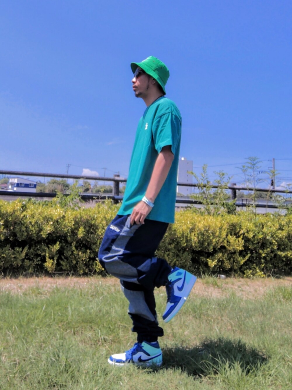 グリーン系のTシャツ/カットソー、ブルー系のデニムパンツ、ブルー系のスニーカーを着用したメンズの夏コーディネートの2枚目の写真