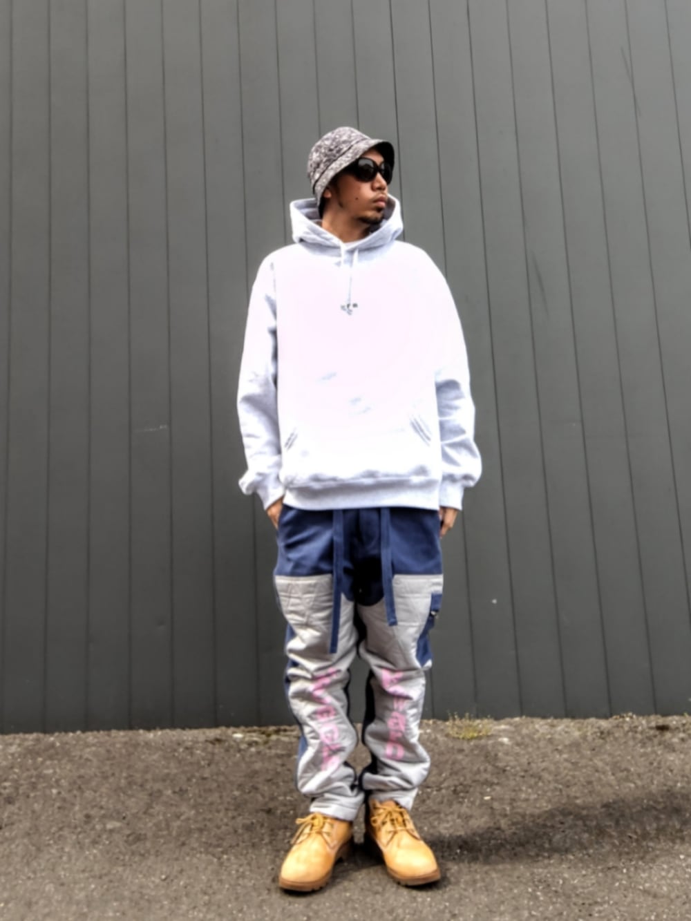 グレー系のパーカー、ブルー系のカーゴパンツ、イエロー系のブーツを着用したメンズの春コーディネートの2枚目の写真