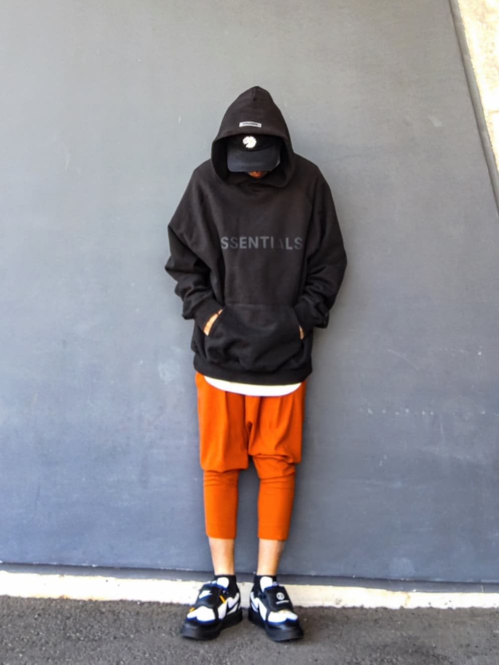 ブラック系のパーカー、ホワイト系のタンクトップ、オレンジ系のその他パンツを着用したメンズの冬コーディネートの2枚目の写真