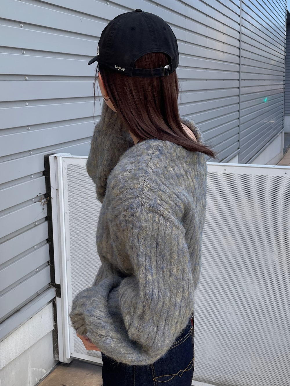 グレー系のニット/セーター、ブルー系のデニムパンツ、ブラック系のネックレスを着用したレディースの秋コーディネートの5枚目の写真