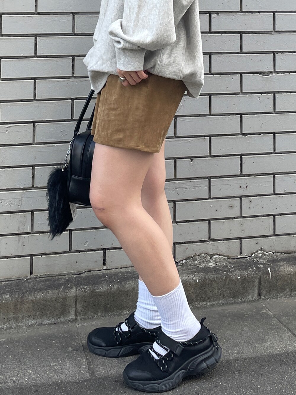 グレー系のスウェット、ベージュ系のスカート、ブラック系のハンドバッグを着用したレディースの秋コーディネートの6枚目の写真