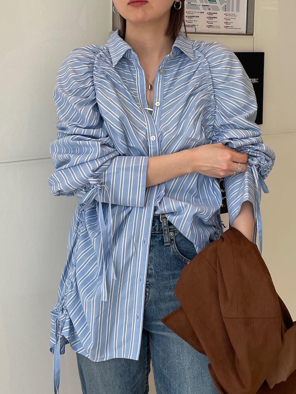 ブラウン系のテーラードジャケット、ブルー系のシャツ/ブラウス、ブルー系のデニムパンツを着用したレディースの春コーディネートの5枚目の写真