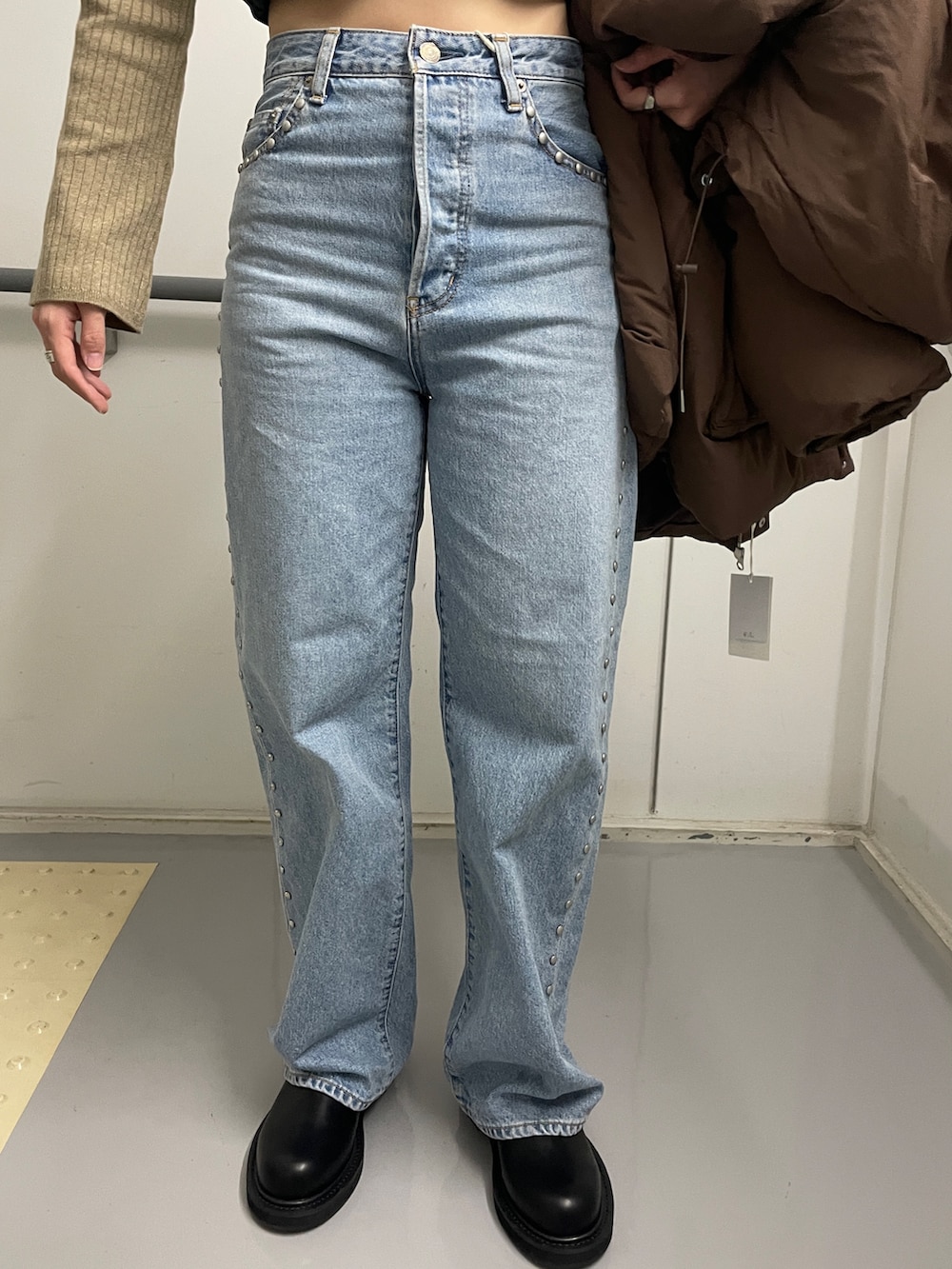 ブルー系のデニムパンツ、ブラック系のブーツ、ブラウン系のダウンジャケット/コートを着用したレディースの秋コーディネートの7枚目の写真