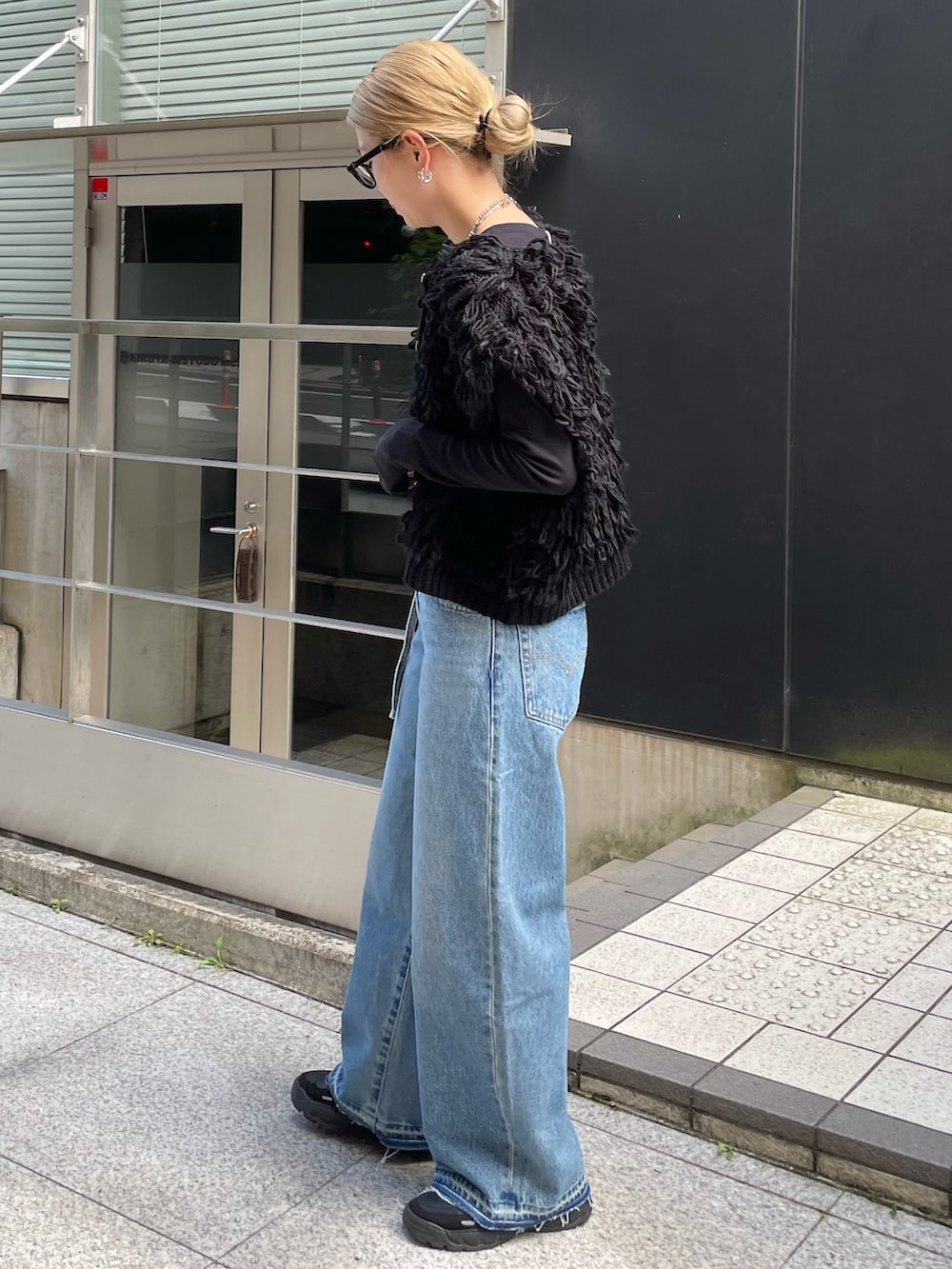 ブルー系のデニムパンツ、ブラック系のベスト、ブラック系のTシャツ/カットソーを着用したレディースの秋コーディネートの3枚目の写真