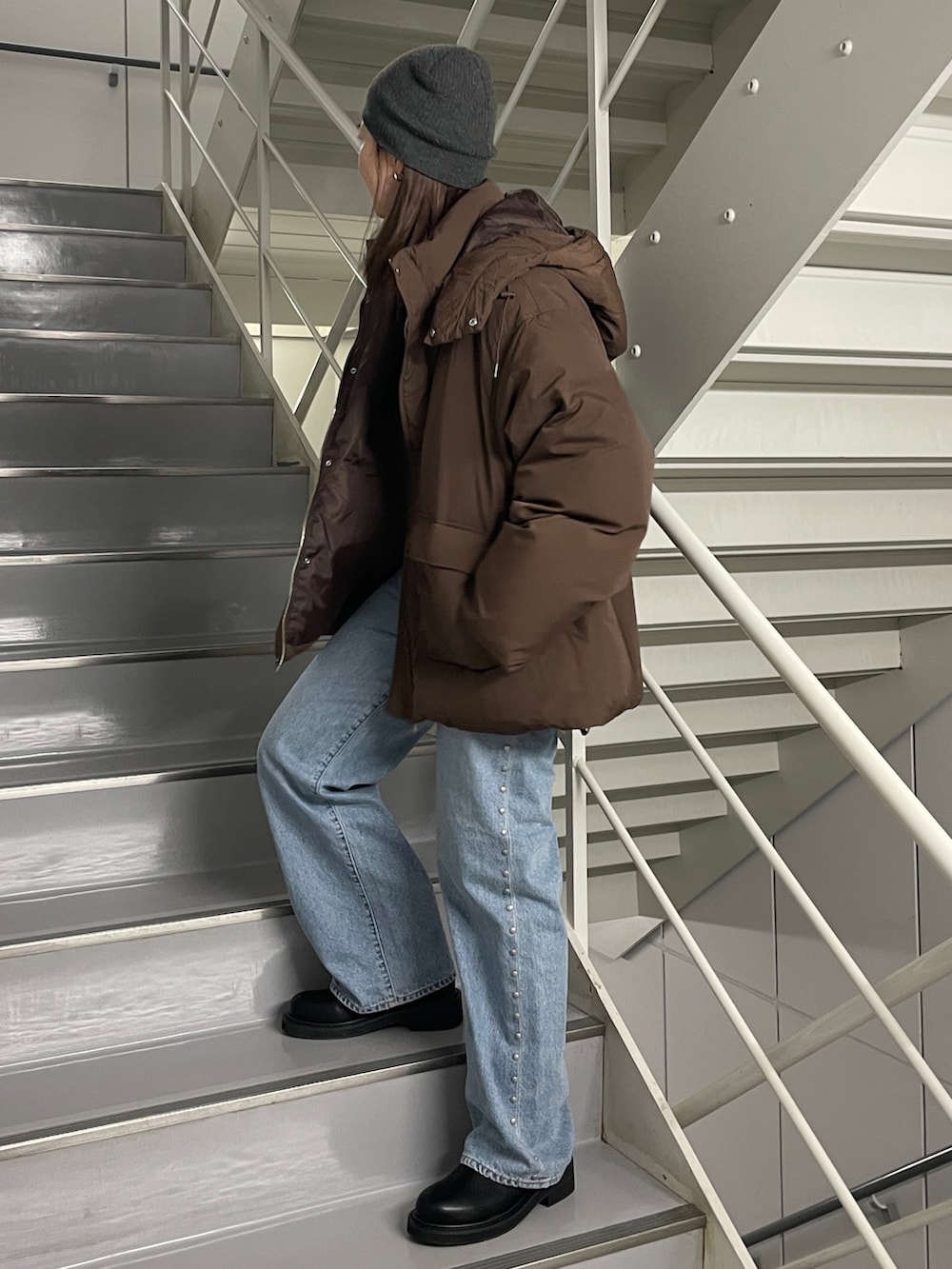 ブルー系のデニムパンツ、ブラック系のブーツ、ブラウン系のダウンジャケット/コートを着用したレディースの秋コーディネートの2枚目の写真