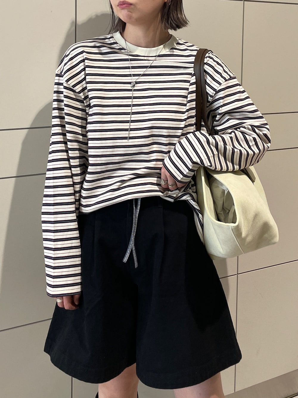 グレー系のトレンチコート、ブラック系のその他パンツ、ブラウン系のトートバッグを着用したレディースの冬コーディネートの9枚目の写真