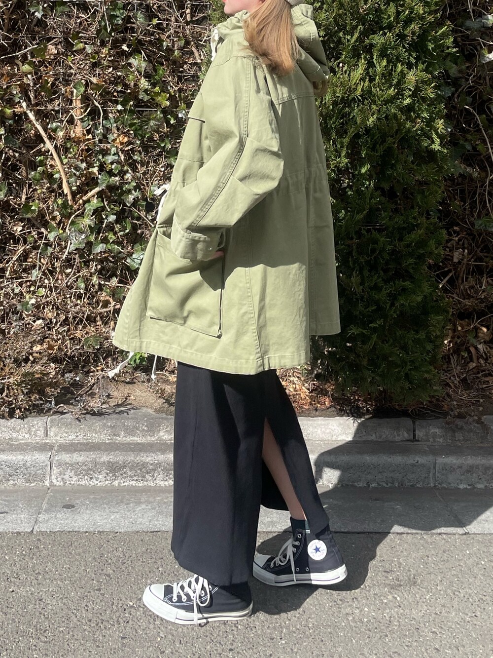 グリーン系のブルゾン、ブラック系のワンピース、ホワイト系のニットキャップ/ビーニーを着用したレディースの冬コーディネートの3枚目の写真