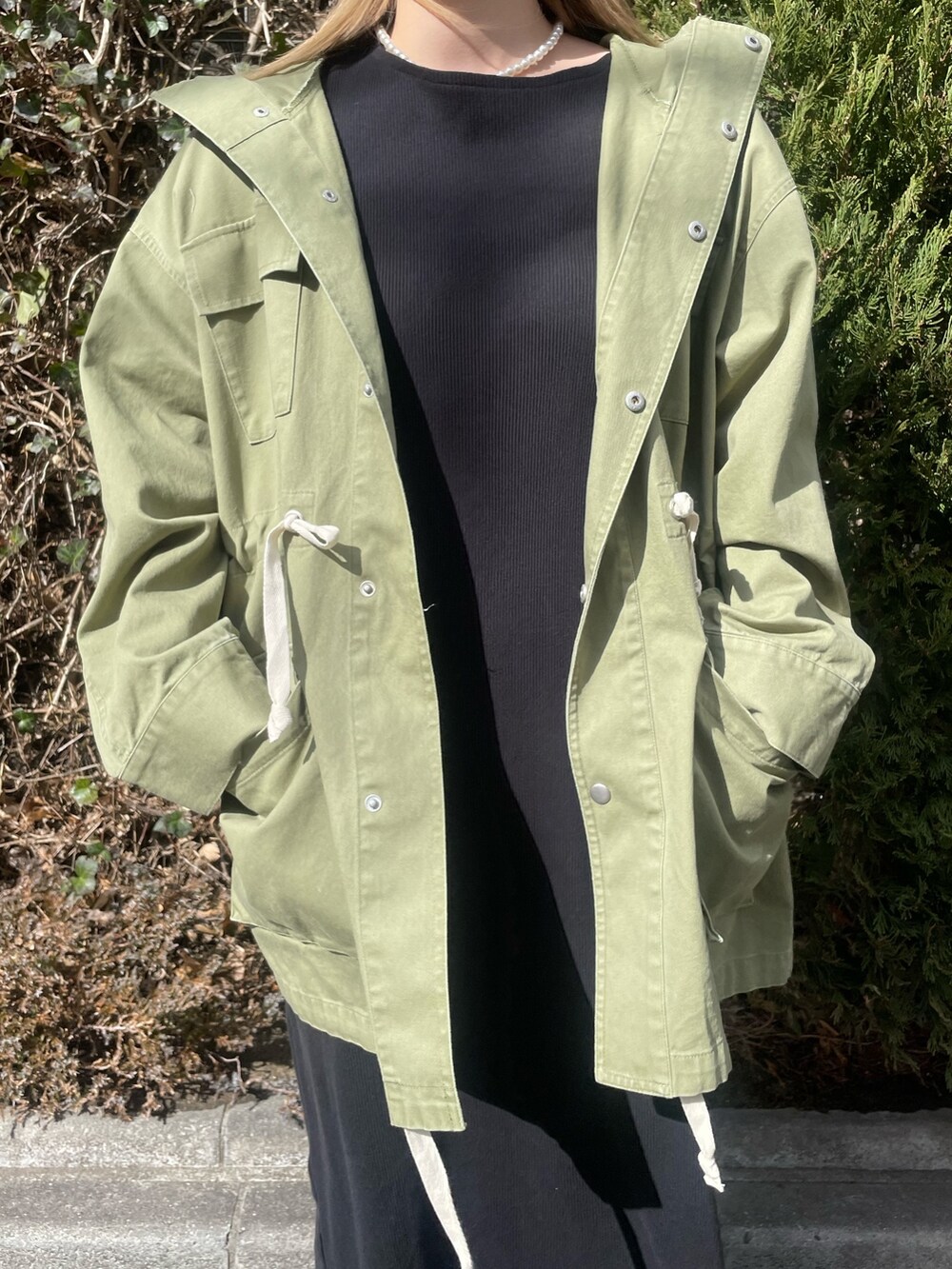 グリーン系のブルゾン、ブラック系のワンピース、ホワイト系のニットキャップ/ビーニーを着用したレディースの冬コーディネートの5枚目の写真