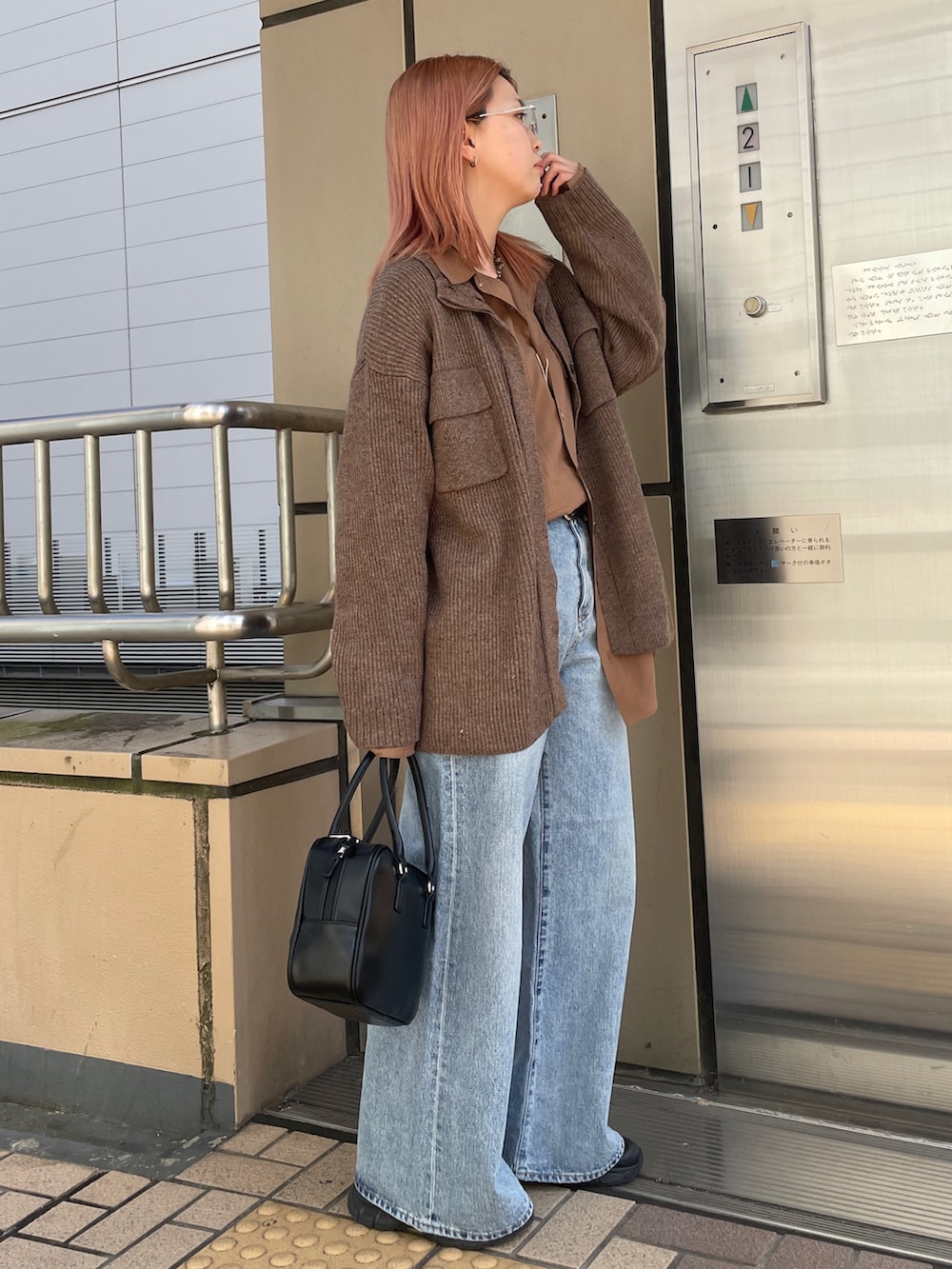 ブラウン系のカーディガン/ボレロ、ブルー系のデニムパンツ、ブラック系のハンドバッグを着用したレディースの秋コーディネートの4枚目の写真