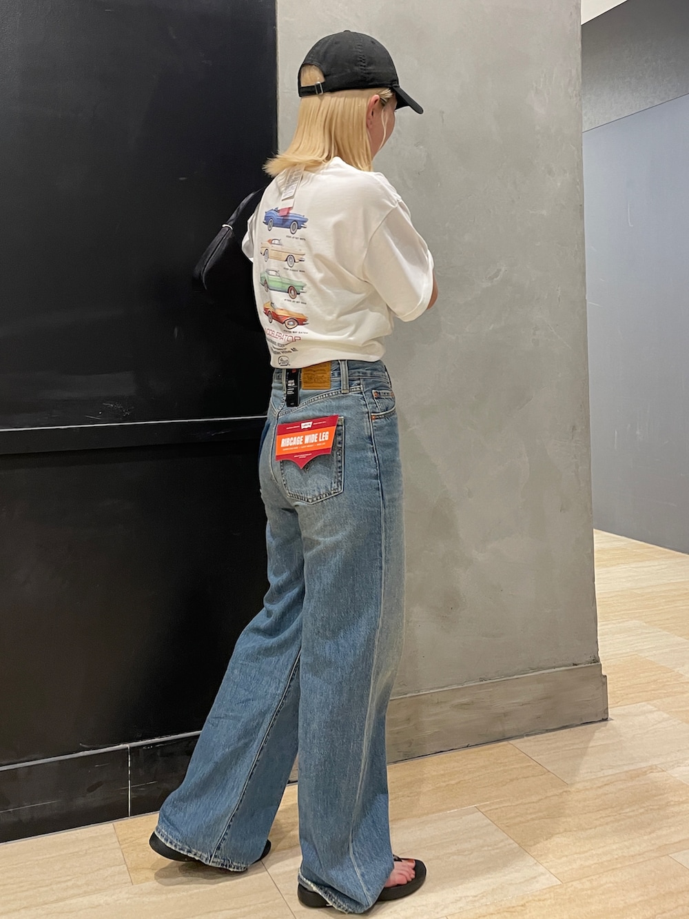 ブルー系のデニムパンツ、ホワイト系のTシャツ/カットソー、ブラック系のハンドバッグを着用したレディースの夏コーディネートの2枚目の写真