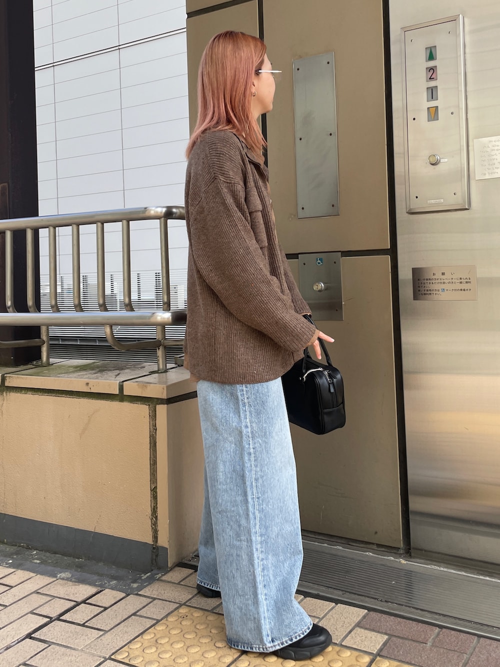 ブラウン系のカーディガン/ボレロ、ブルー系のデニムパンツ、ブラック系のハンドバッグを着用したレディースの秋コーディネートの3枚目の写真