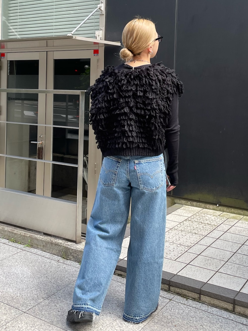 ブルー系のデニムパンツ、ブラック系のベスト、ブラック系のTシャツ/カットソーを着用したレディースの秋コーディネートの4枚目の写真