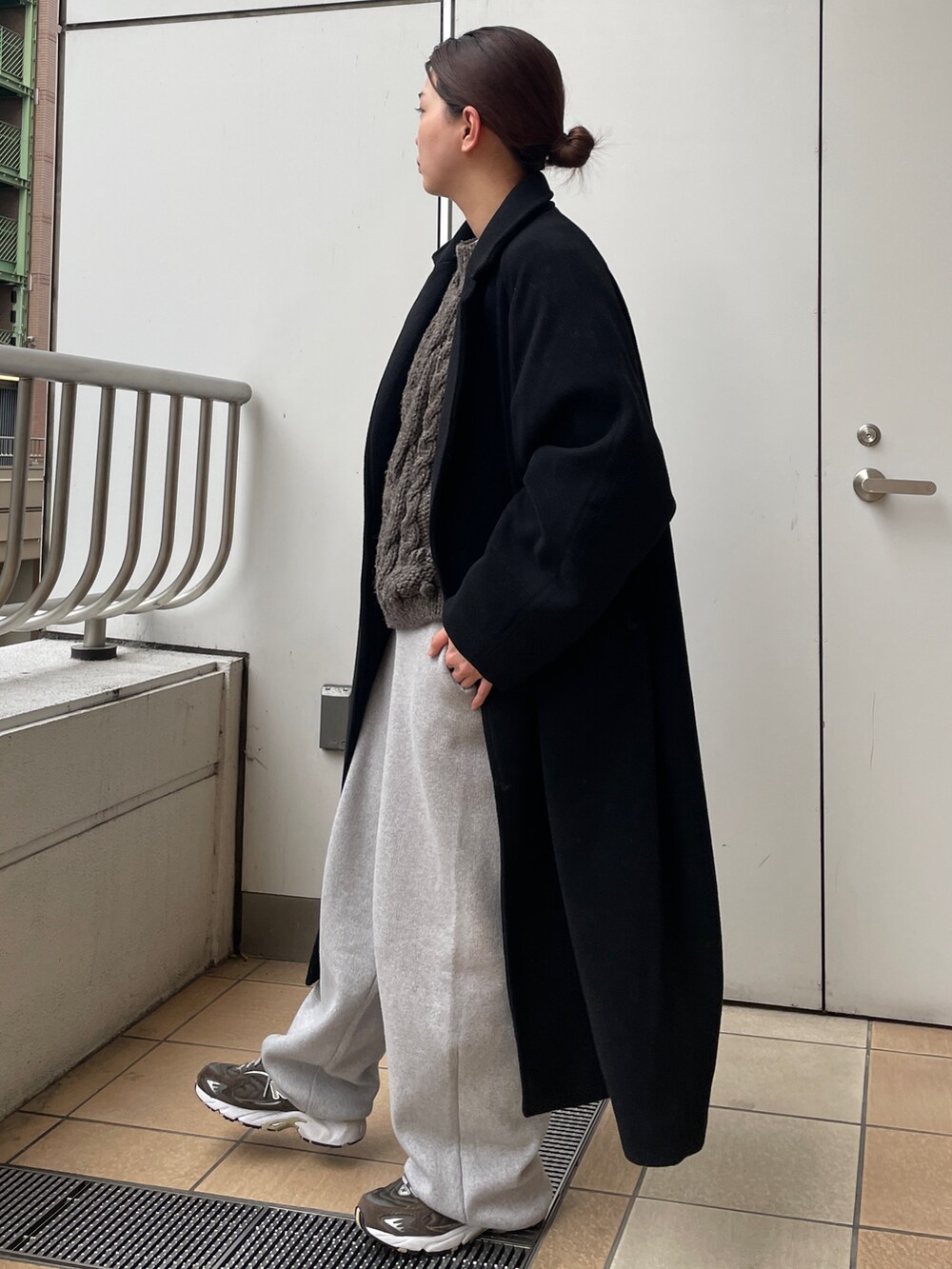 ブラック系のチェスターコート、グレー系のその他パンツ、ブラック系のハンドバッグを着用したレディースの冬コーディネートの2枚目の写真