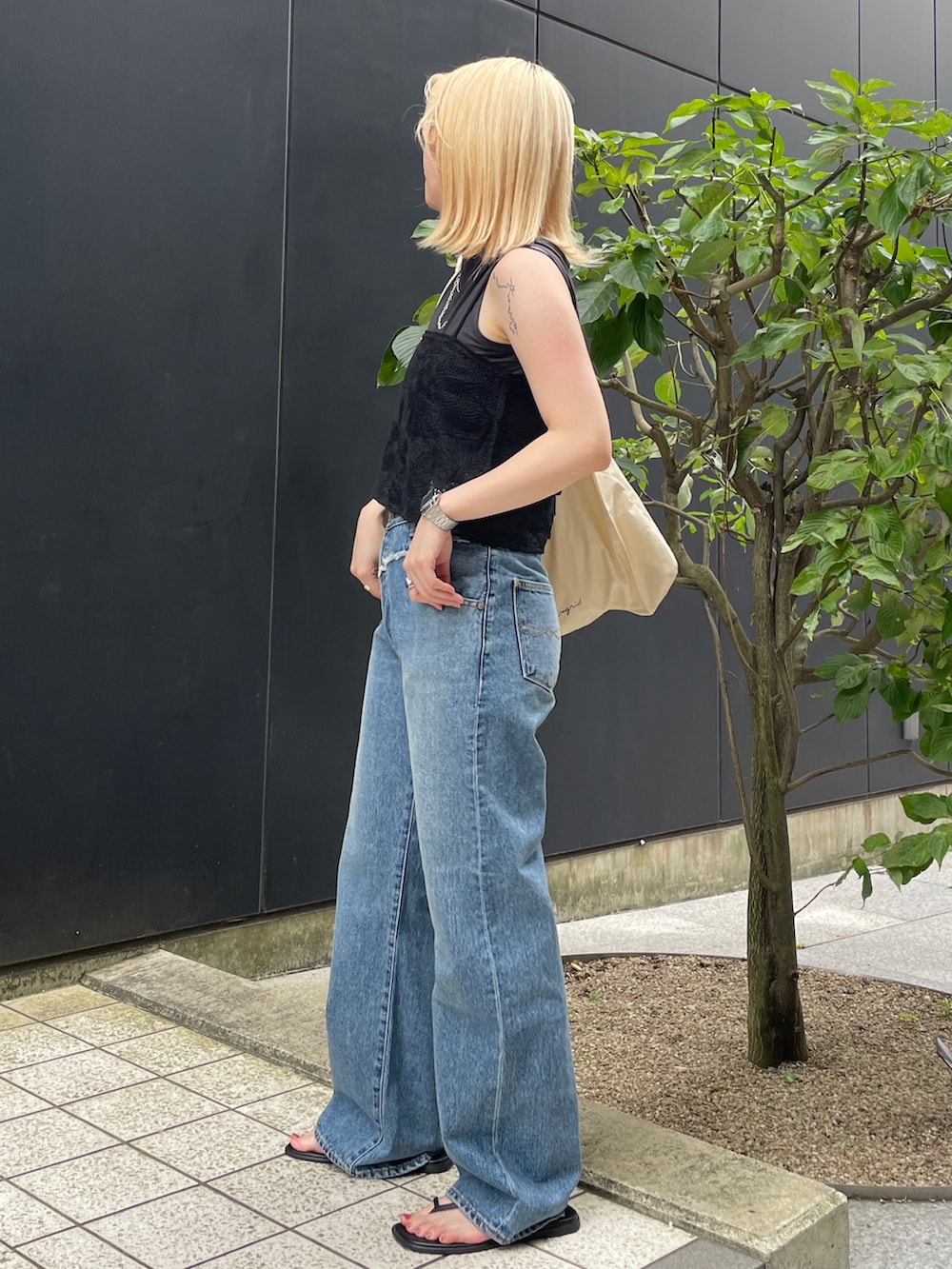 ブルー系のデニムパンツ、ブラック系のタンクトップ、ブラック系のキャミソールを着用したレディースの夏コーディネートの2枚目の写真