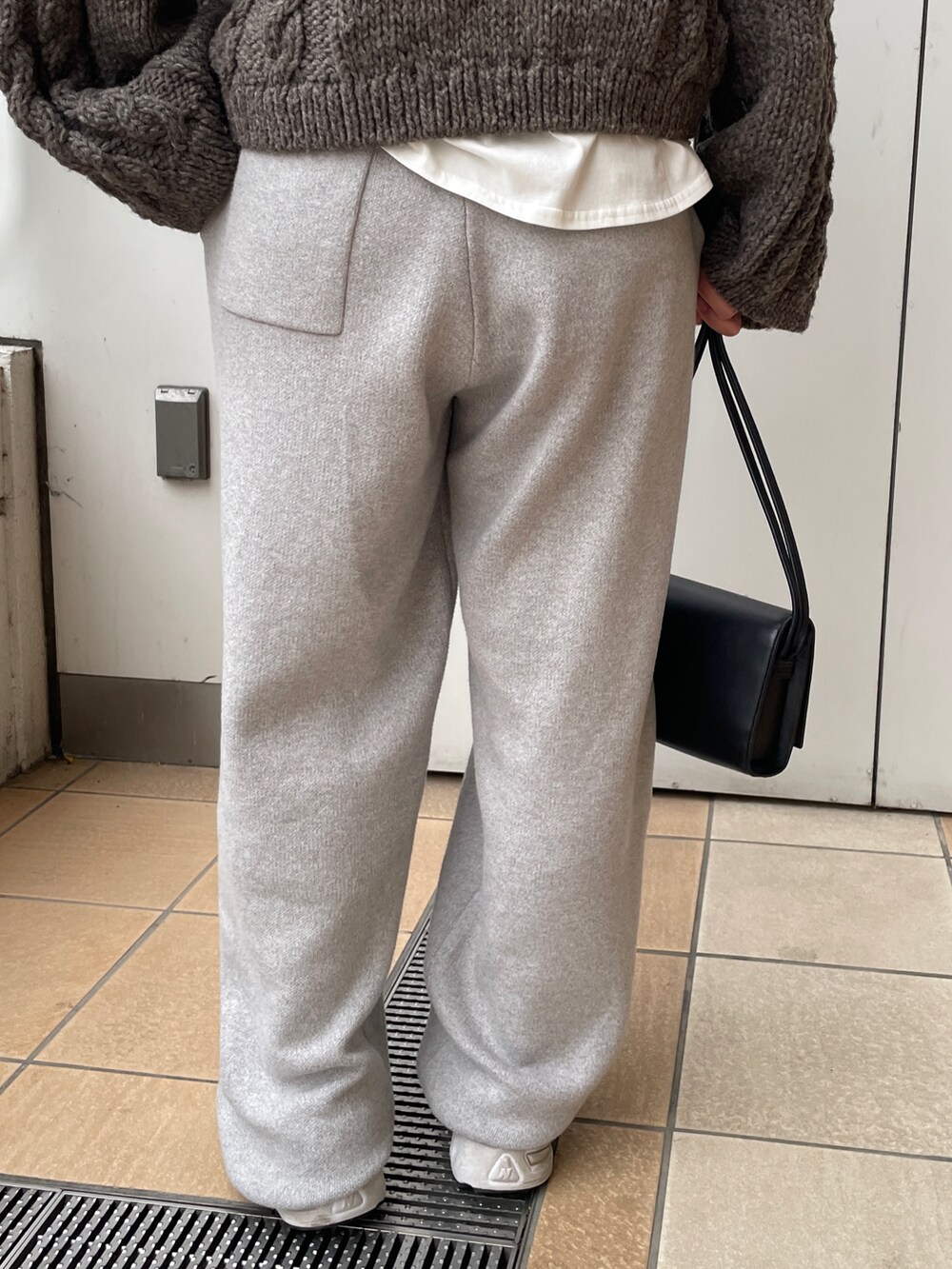 ブラック系のチェスターコート、グレー系のその他パンツ、ブラック系のハンドバッグを着用したレディースの冬コーディネートの6枚目の写真