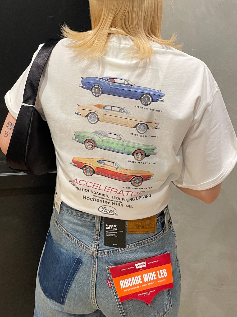 ブルー系のデニムパンツ、ホワイト系のTシャツ/カットソー、ブラック系のハンドバッグを着用したレディースの夏コーディネートの5枚目の写真