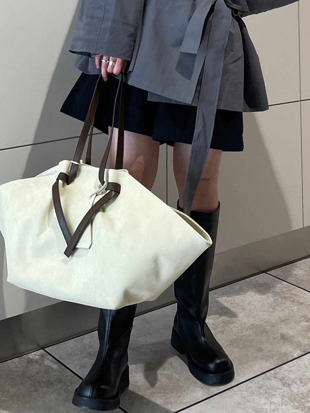 グレー系のトレンチコート、ブラック系のその他パンツ、ブラウン系のトートバッグを着用したレディースの冬コーディネートの7枚目の写真