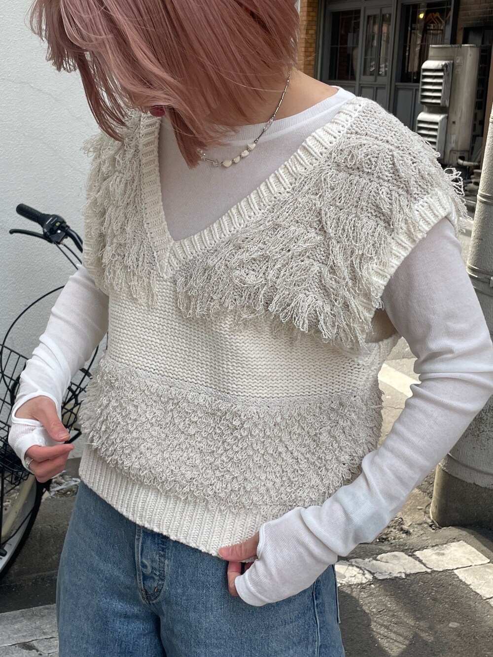 ブルー系のデニムパンツ、ホワイト系のベスト、ホワイト系のTシャツ/カットソーを着用したレディースの冬コーディネートの4枚目の写真