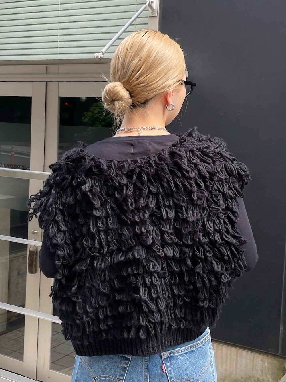 ブルー系のデニムパンツ、ブラック系のベスト、ブラック系のTシャツ/カットソーを着用したレディースの秋コーディネートの6枚目の写真