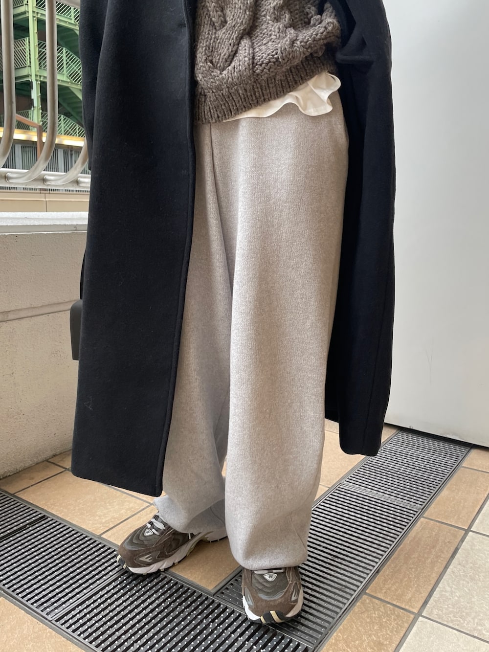 ブラック系のチェスターコート、グレー系のその他パンツ、ブラック系のハンドバッグを着用したレディースの冬コーディネートの4枚目の写真