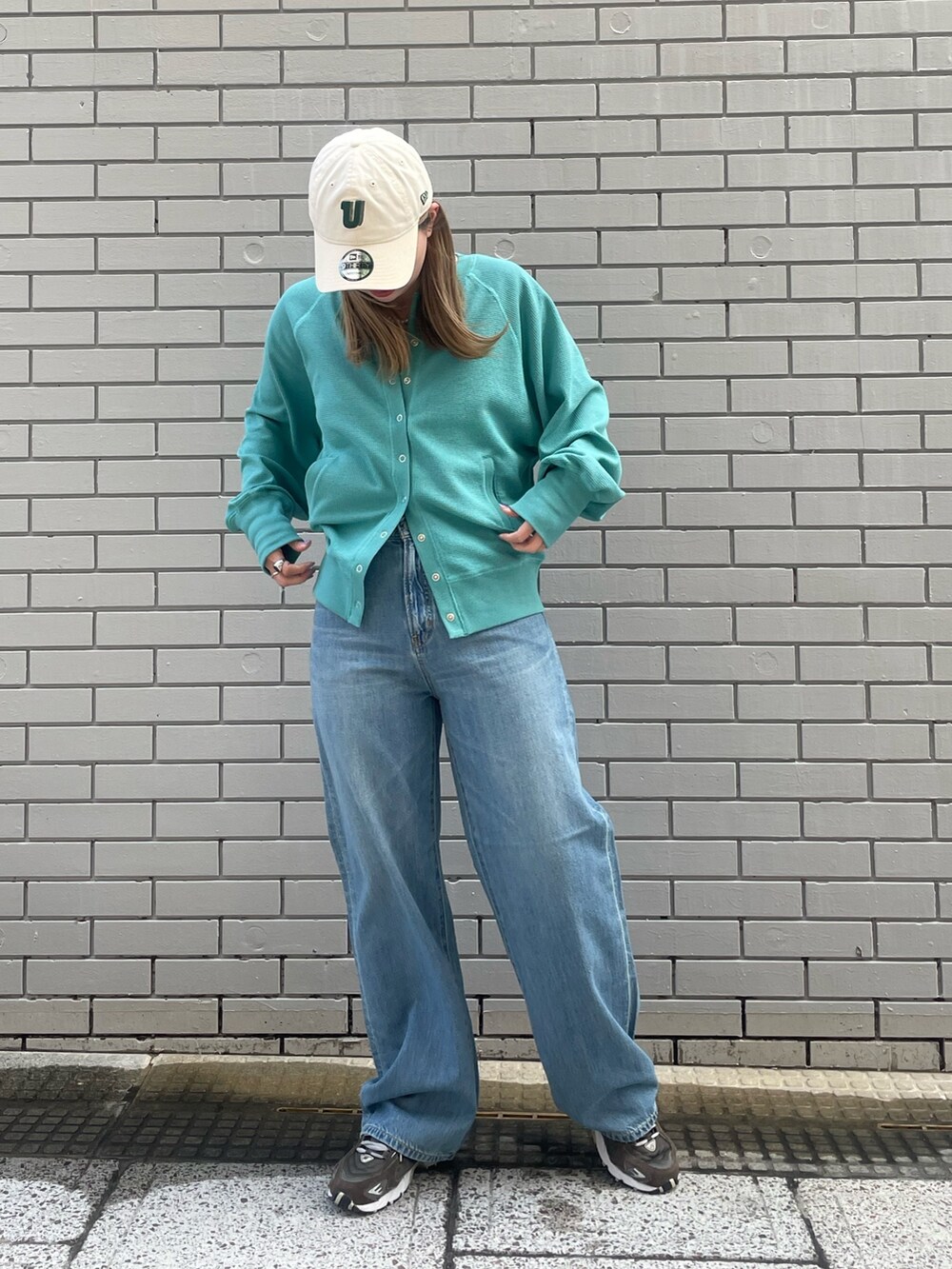 ブルー系のカーディガン/ボレロ、ブルー系のデニムパンツ、ホワイト系のキャップを着用したレディースの冬コーディネートの2枚目の写真