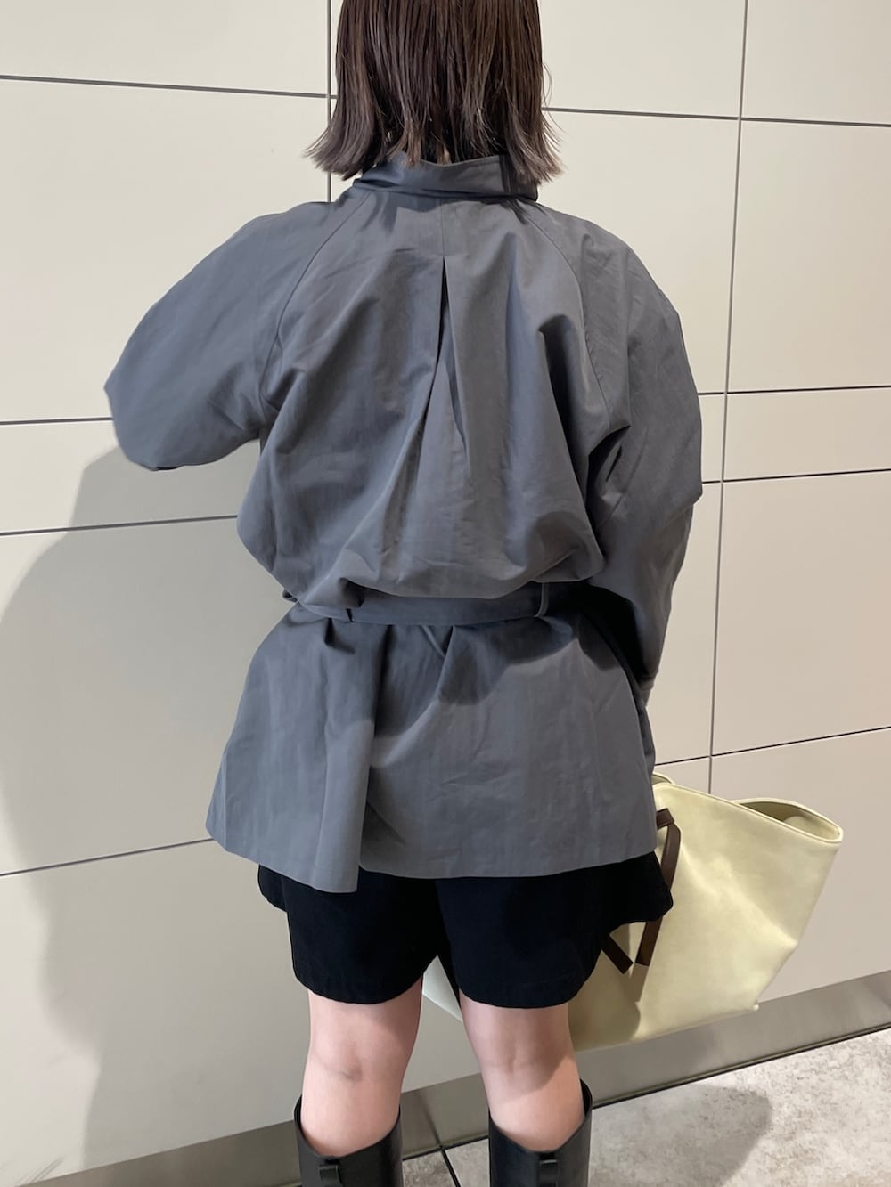 グレー系のトレンチコート、ブラック系のその他パンツ、ブラウン系のトートバッグを着用したレディースの冬コーディネートの6枚目の写真