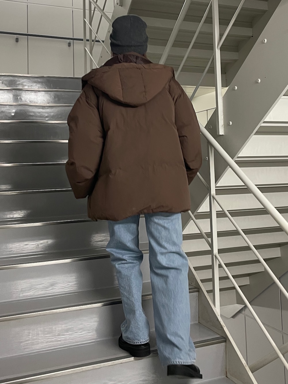 ブルー系のデニムパンツ、ブラック系のブーツ、ブラウン系のダウンジャケット/コートを着用したレディースの秋コーディネートの3枚目の写真