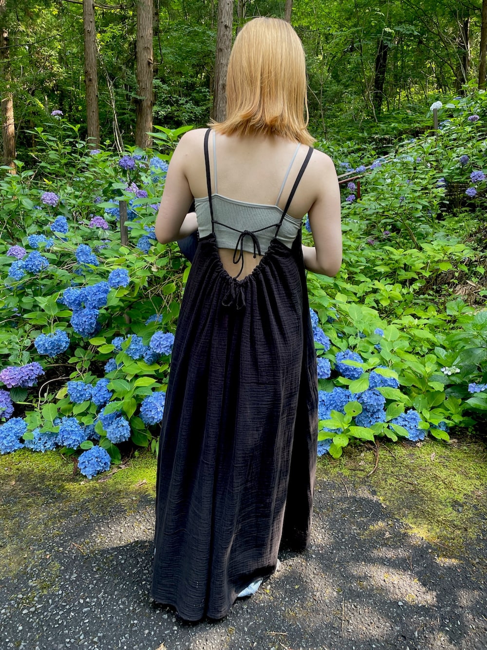 ブラック系のワンピース、ブルー系のデニムパンツ、ブラック系のサンダルを着用したレディースの夏コーディネートの2枚目の写真