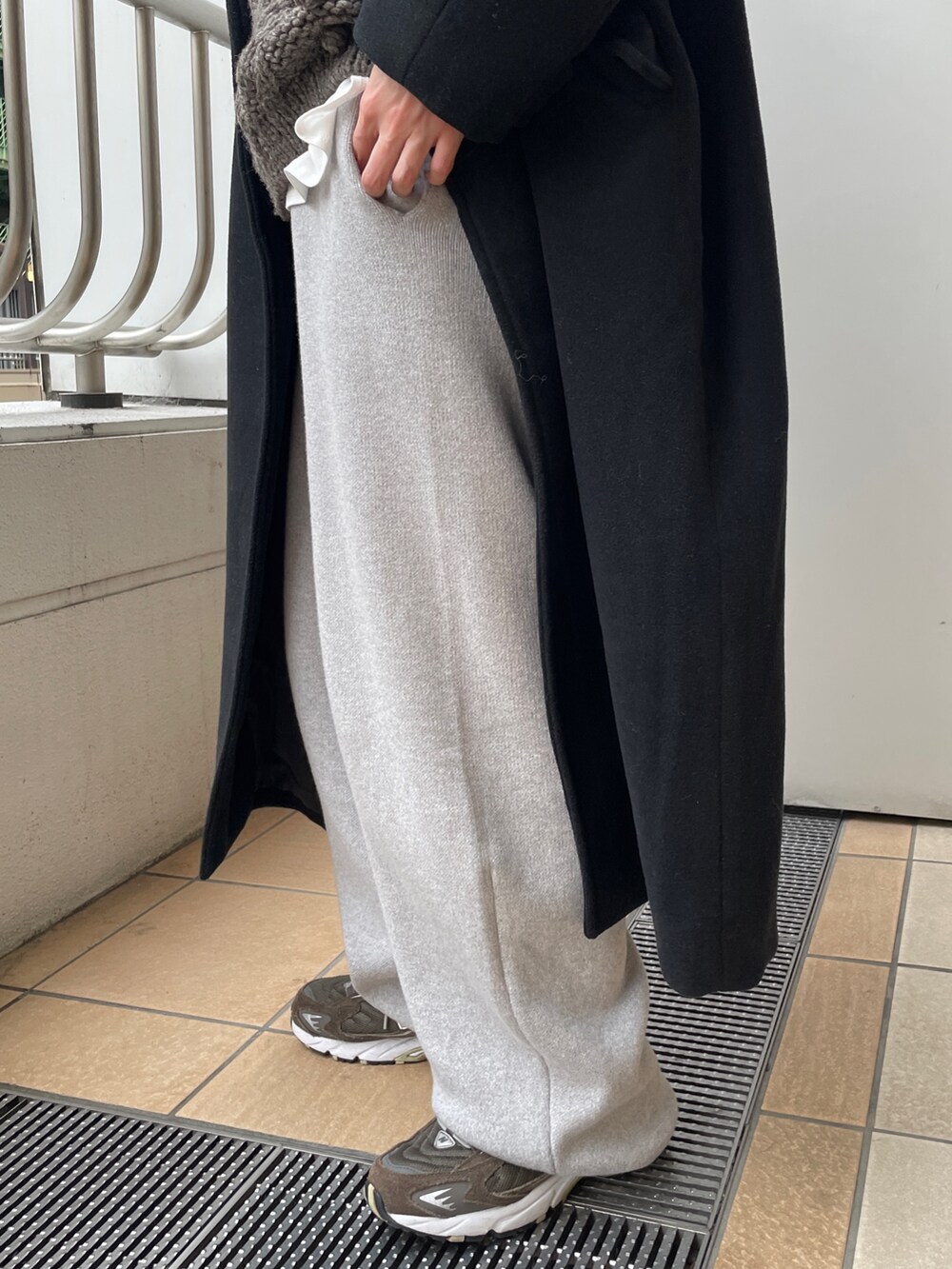 ブラック系のチェスターコート、グレー系のその他パンツ、ブラック系のハンドバッグを着用したレディースの冬コーディネートの5枚目の写真