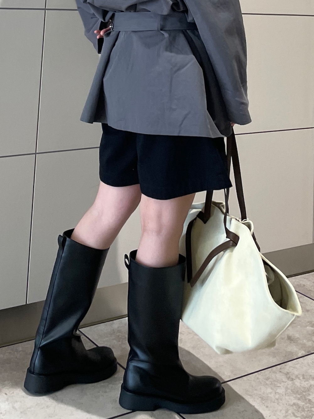 グレー系のトレンチコート、ブラック系のその他パンツ、ブラウン系のトートバッグを着用したレディースの冬コーディネートの8枚目の写真