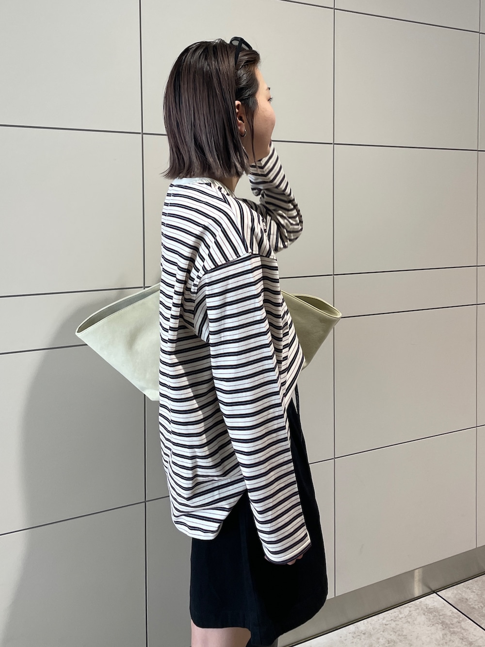 グレー系のトレンチコート、ブラック系のその他パンツ、ブラウン系のトートバッグを着用したレディースの冬コーディネートの10枚目の写真