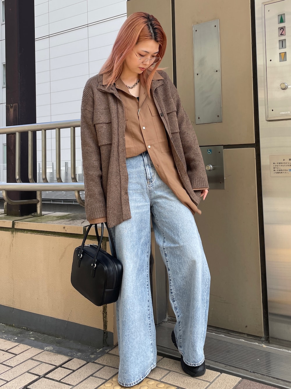 ブラウン系のカーディガン/ボレロ、ブルー系のデニムパンツ、ブラック系のハンドバッグを着用したレディースの秋コーディネートの2枚目の写真