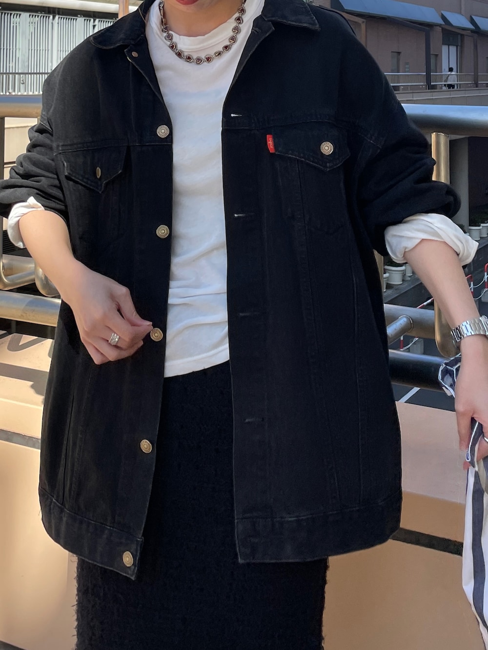 ブラック系のデニムジャケット、ホワイト系のTシャツ/カットソー、ブラック系のスカートを着用したレディースの秋コーディネートの4枚目の写真