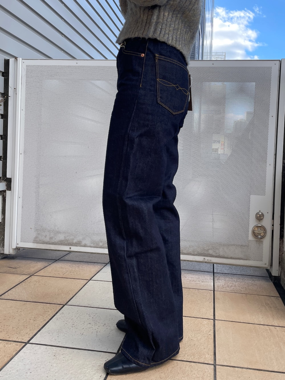 グレー系のニット/セーター、ブルー系のデニムパンツ、ブラック系のネックレスを着用したレディースの秋コーディネートの8枚目の写真