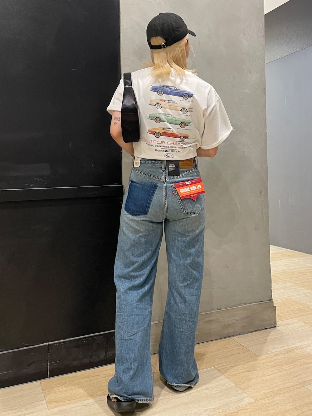 ブルー系のデニムパンツ、ホワイト系のTシャツ/カットソー、ブラック系のハンドバッグを着用したレディースの夏コーディネートの3枚目の写真