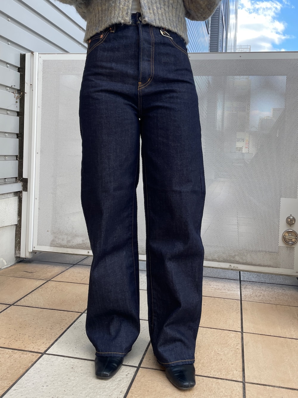 グレー系のニット/セーター、ブルー系のデニムパンツ、ブラック系のネックレスを着用したレディースの秋コーディネートの7枚目の写真