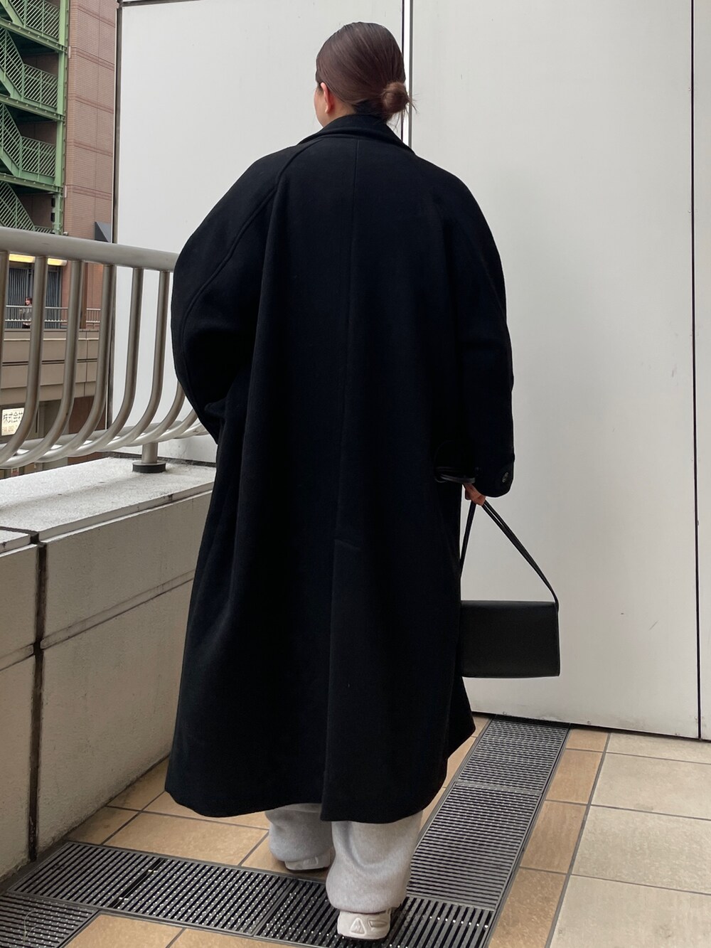 ブラック系のチェスターコート、グレー系のその他パンツ、ブラック系のハンドバッグを着用したレディースの冬コーディネートの3枚目の写真